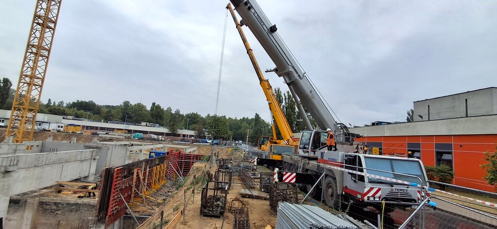 Żurawie samojezdne i dźwig wieżowy podczas prac budowlanych w Łodzi